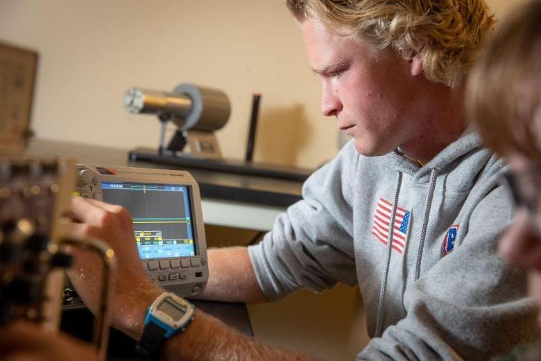 Male Physics student studying data on a monitor.